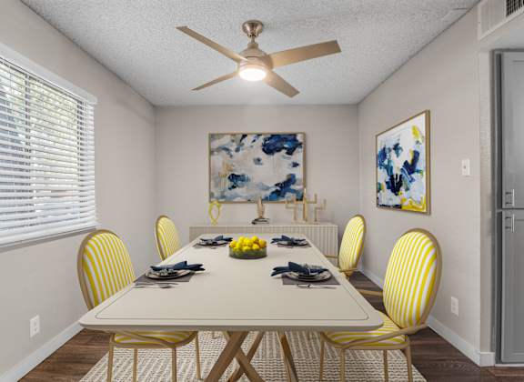 A dining room with a white table and yellow chairs.
