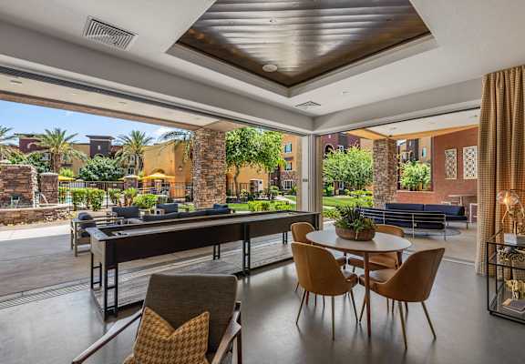 a patio with a table and chairs and a pool in the background