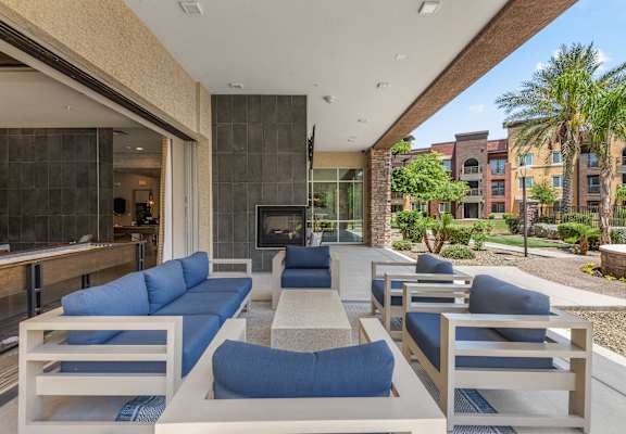 a patio with blue couches and chairs and a fireplace