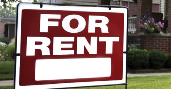 a red for rent sign in front of a house