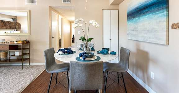 A dining room with a table set for two and a painting on the wall.