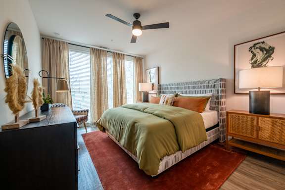 A bedroom with a bed, a dresser, and a ceiling fan.