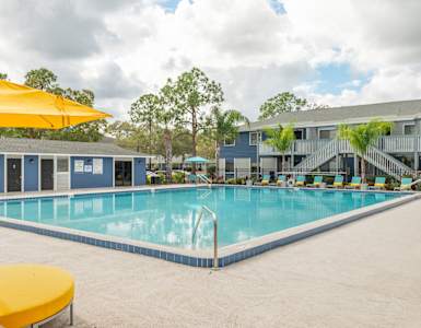 our resort style swimming pool is surrounded by our buildings and yellow umbrellas