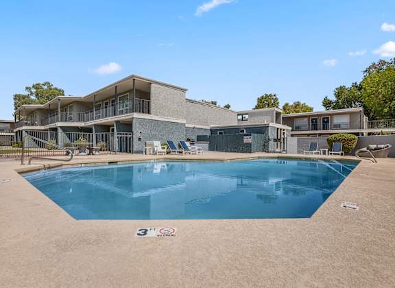 a swimming pool in front of a house with a building in the background