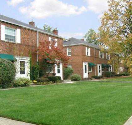 A long brick building with a green awning sits next to a sidewalk.