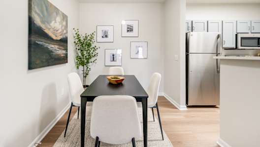 A dining room with a black table and white chairs.