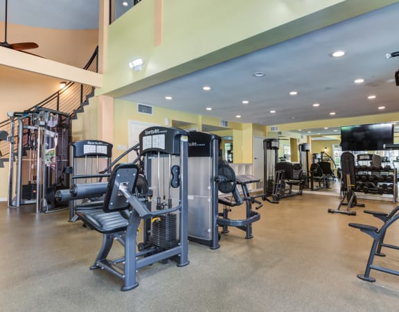 a spacious fitness center with cardio equipment and a spiral staircase