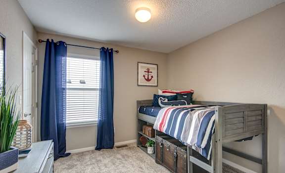 A room with a bunk bed and a window with blue curtains.
