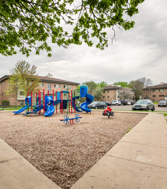 A playground with a slide, swings, and a seesaw.