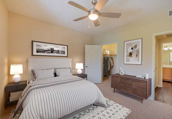 A bedroom with a large bed, a ceiling fan, and a painting on the wall. at  Ventana Senior Apartments, Porter Ranch ,91326