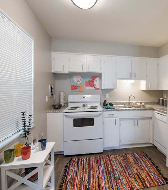 A small kitchen with white cabinets and a white fridge.