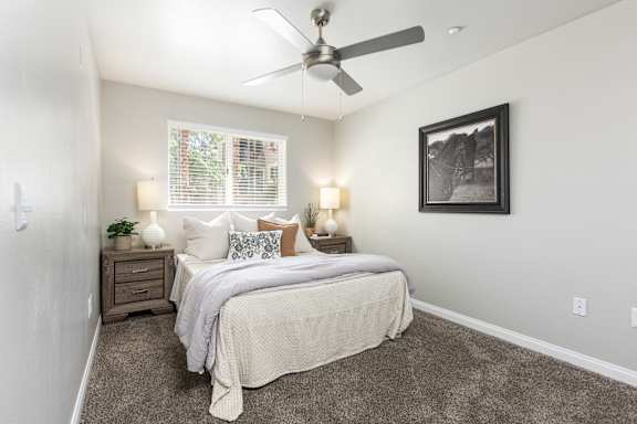 A bedroom with a bed, two lamps, and two pictures on the wall.
