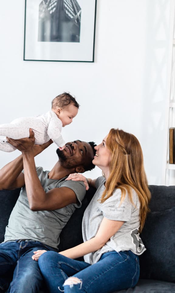 a mother and father playing with their baby on the couch