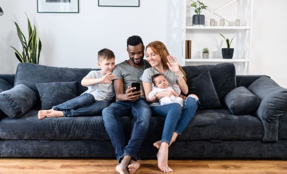 a family sitting on a couch while looking at a cell phone