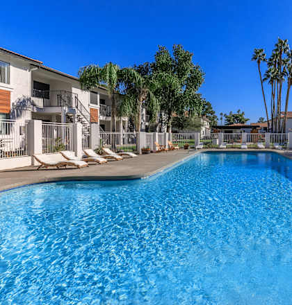 a large swimming pool with palm trees and apartments in the background