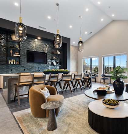 A modern living room with a stone fireplace and a variety of seating options.