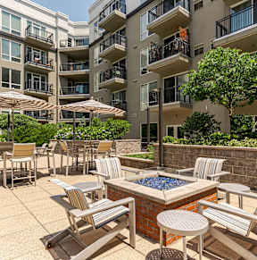 A fire pit surrounded by four blue chairs.