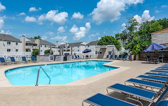 a large pool with lounge chairs and umbrellas in front of a building at Candles, Springfield, 62704