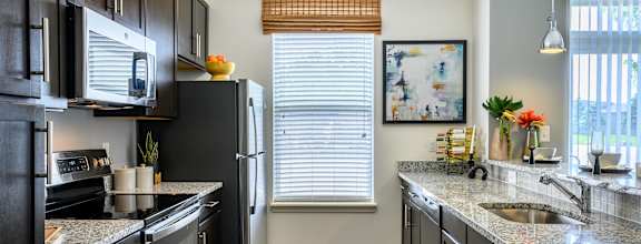 A kitchen with black cabinets and granite countertops. at Penn Circle, Carmel, IN, 46032