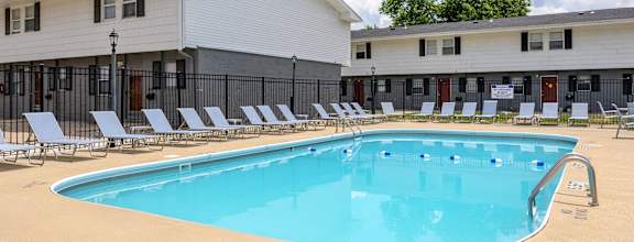 A large swimming pool with lounge chairs in front of a white building at Spring Creek Townhomes, Illinois, 62702