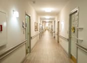 Thumbnail 22 of 31 - A long hallway with doors on both sides and pictures on the wall.