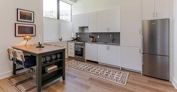 A kitchen with a refrigerator, oven, and sink.