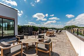 A wooden deck with chairs and tables overlooking a cityscape.