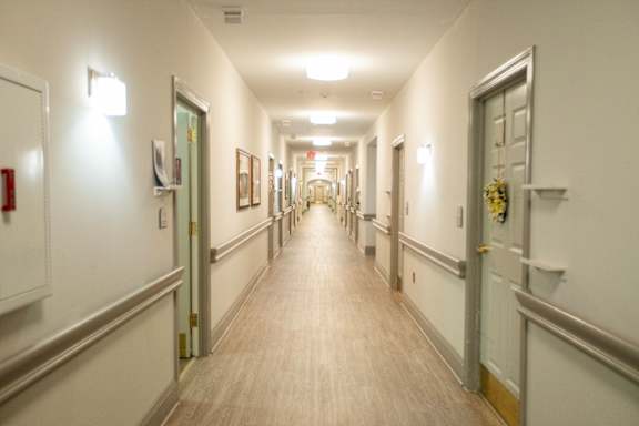 A long hallway with doors on both sides and pictures on the wall.