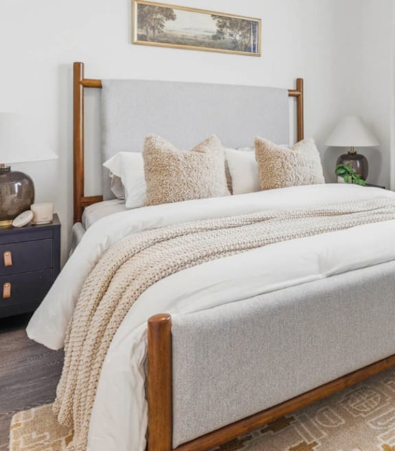 A bed with a white blanket and pillows in a room.