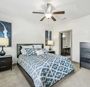 A bedroom with a bed, nightstand, and a ceiling fan.