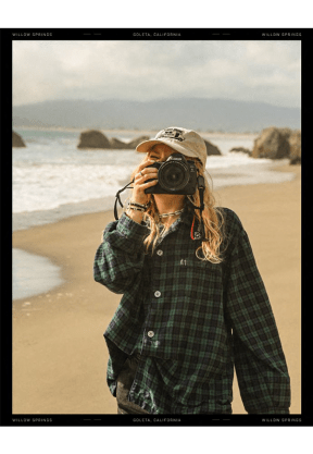 a woman taking a picture on the beach with a camera