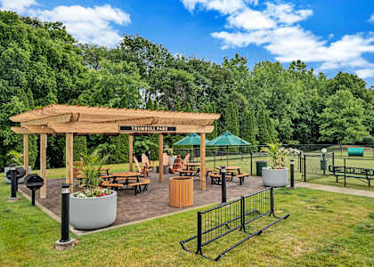 a pavilion with a seating area and a dog park in the background
