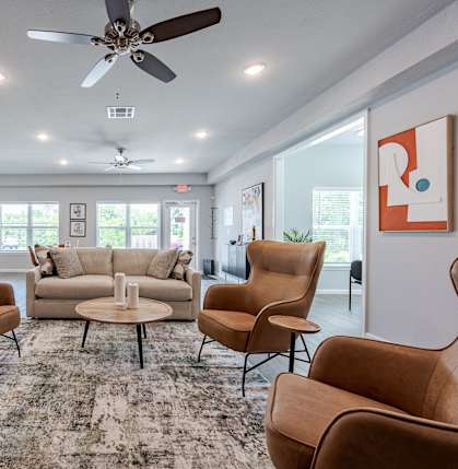 a living room with couches and chairs and a ceiling fan