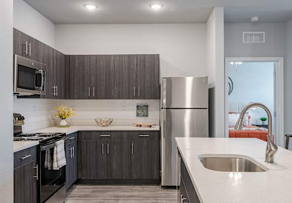 an updated kitchen with stainless steel appliances and white countertops