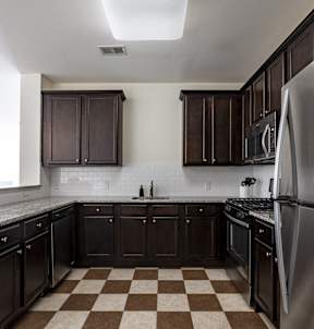 A kitchen with black cabinets and a checkered floor.