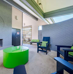 a lounge area with a fireplace and chairs and a green table