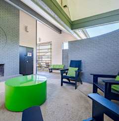 a lounge area with a fireplace and chairs and a green table