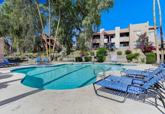a swimming pool with blue lounge chairs and a building in the background at Desert Bay Apartments, Laughlin, NV, 89029