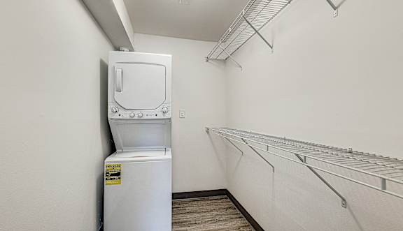 A white industrial freezer sits in a room with a metal shelving unit along the wall.