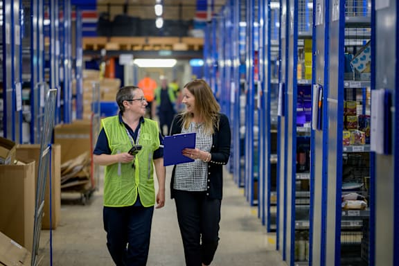 A man and a woman are walking in a warehouse.