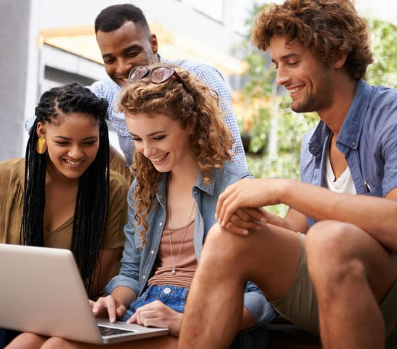 a group of people sitting around a laptop computer