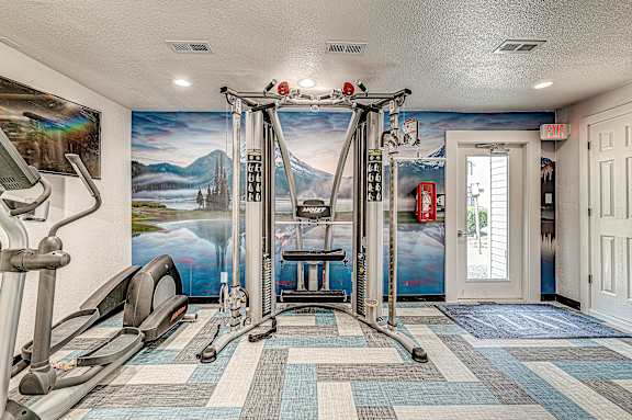 A gym with a treadmill, elliptical trainer, and other exercise equipment.