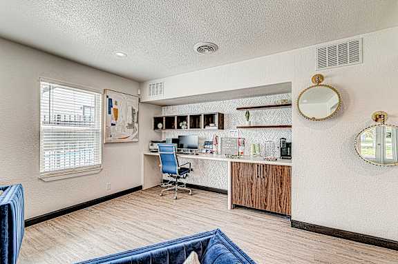 A room with a blue chair and a desk with a computer.