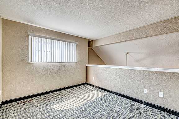 A room with a carpeted floor and a window with blinds.