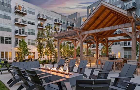 A modern outdoor seating area with a fire pit and chairs.