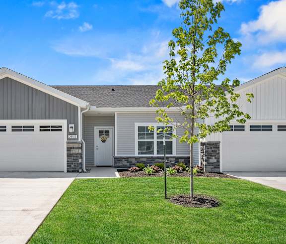 A house with a grey garage door and a tree in front.