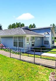 A house with a grey roof and a fence in front of it.