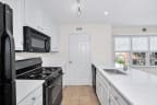 a kitchen with white cabinets and black appliances