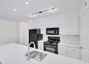 Thumbnail 8 of 9 - a kitchen with white cabinets and black appliances