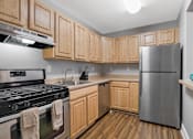 Thumbnail 1 of 3 - A kitchen with wooden cabinets and a stainless steel refrigerator.